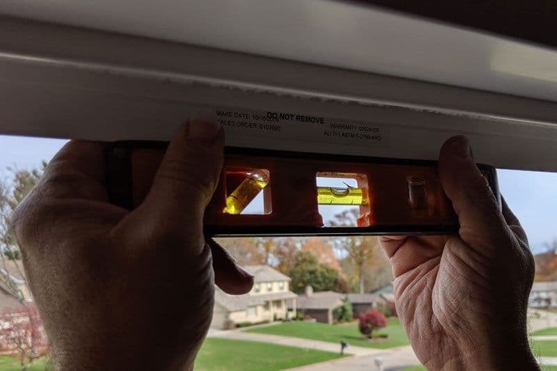 Hand holding film negative up to light with house and landscape visible through amber-toned film frames